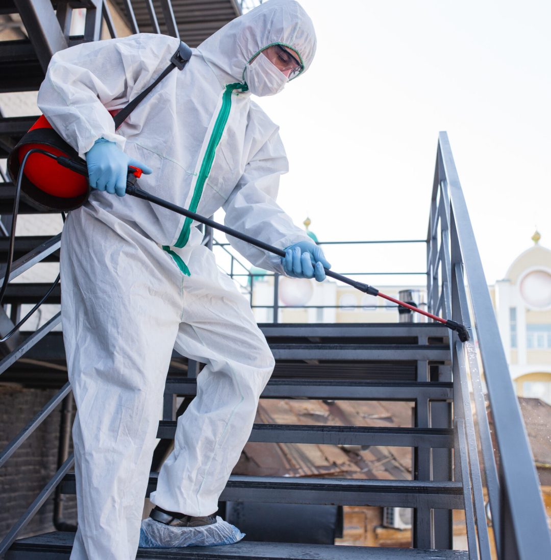 Coronavirus Pandemic. A disinfector in a protective suit and mask sprays disinfectants in the room. Protection of COVID-19 disease. Prevention of spreding pneumonia virus with surfaces we touch.